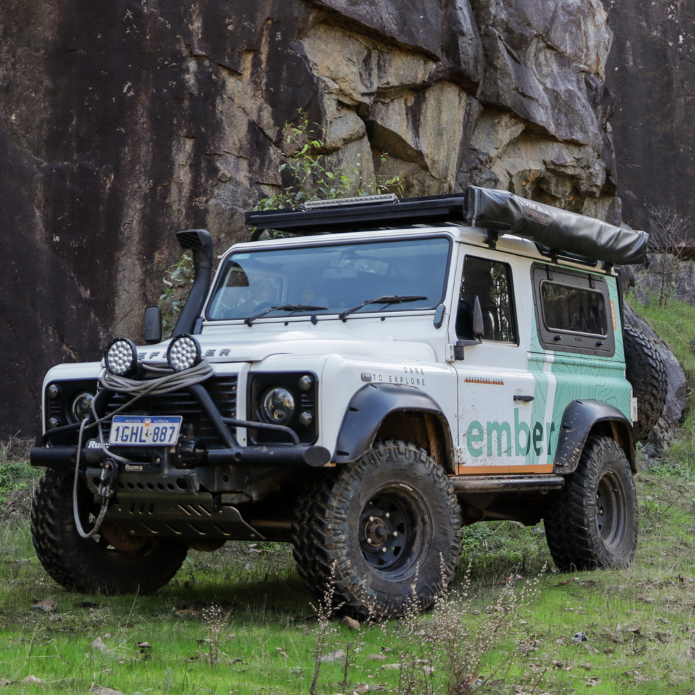 Off-road vehicle with 'emibe' branding parked in a natural setting with rocky cliffs.
