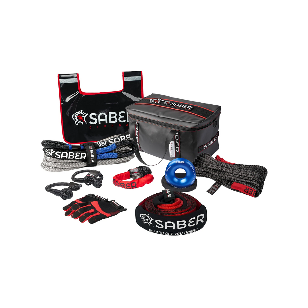 An image displaying the Saber 8K Ultimate Recovery Kit with various components laid out, including a black and red gear bag, a kinetic recovery rope, soft shackles, winch gear, gloves, and a tree trunk protector.