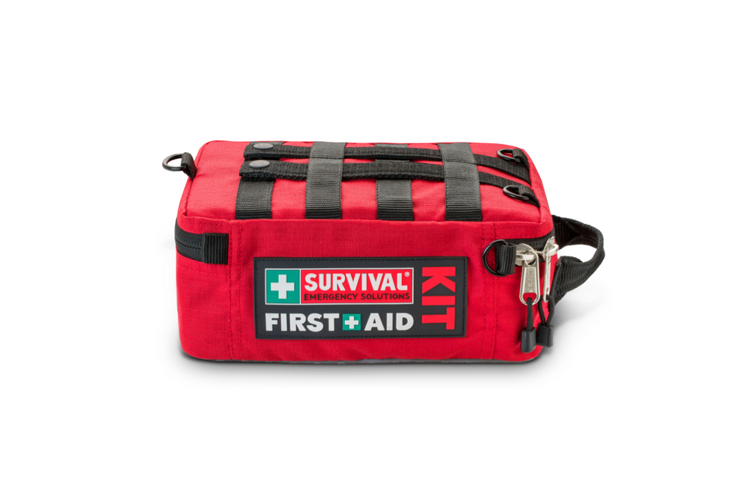 Family Survival First Aid Kit – heavy-duty red case with labeled compartments laying flat showing the molle webbing on the back which is useful for attaching to multiple objects
